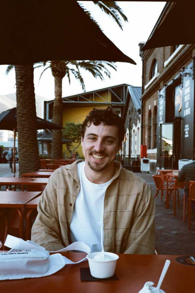 Picture of the creator of the website smiling sitting in a cafe